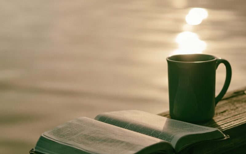 green ceramic mug beside book