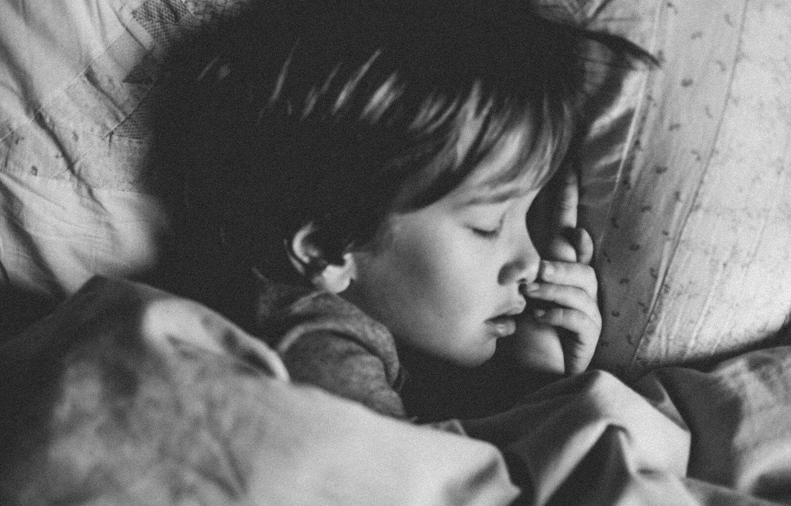 grayscale photo of girl sleeping on white pillow