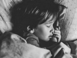 grayscale photo of girl sleeping on white pillow